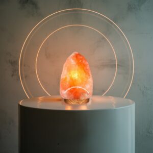 A glowing Himalayan salt lamp sits atop a white pedestal, casting a warm, inviting light in the surrounding space.